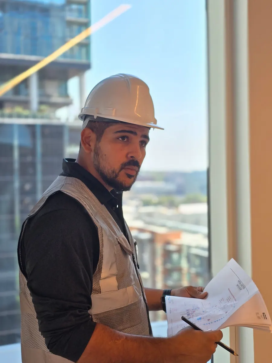Joshua in a hard hat reviewing plans on a high-rise jobsite