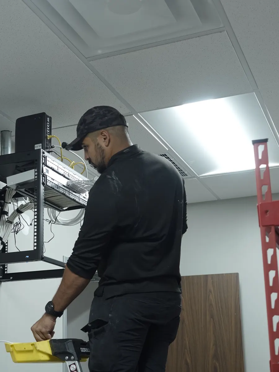 Joshua working on a wall-mounted network rack