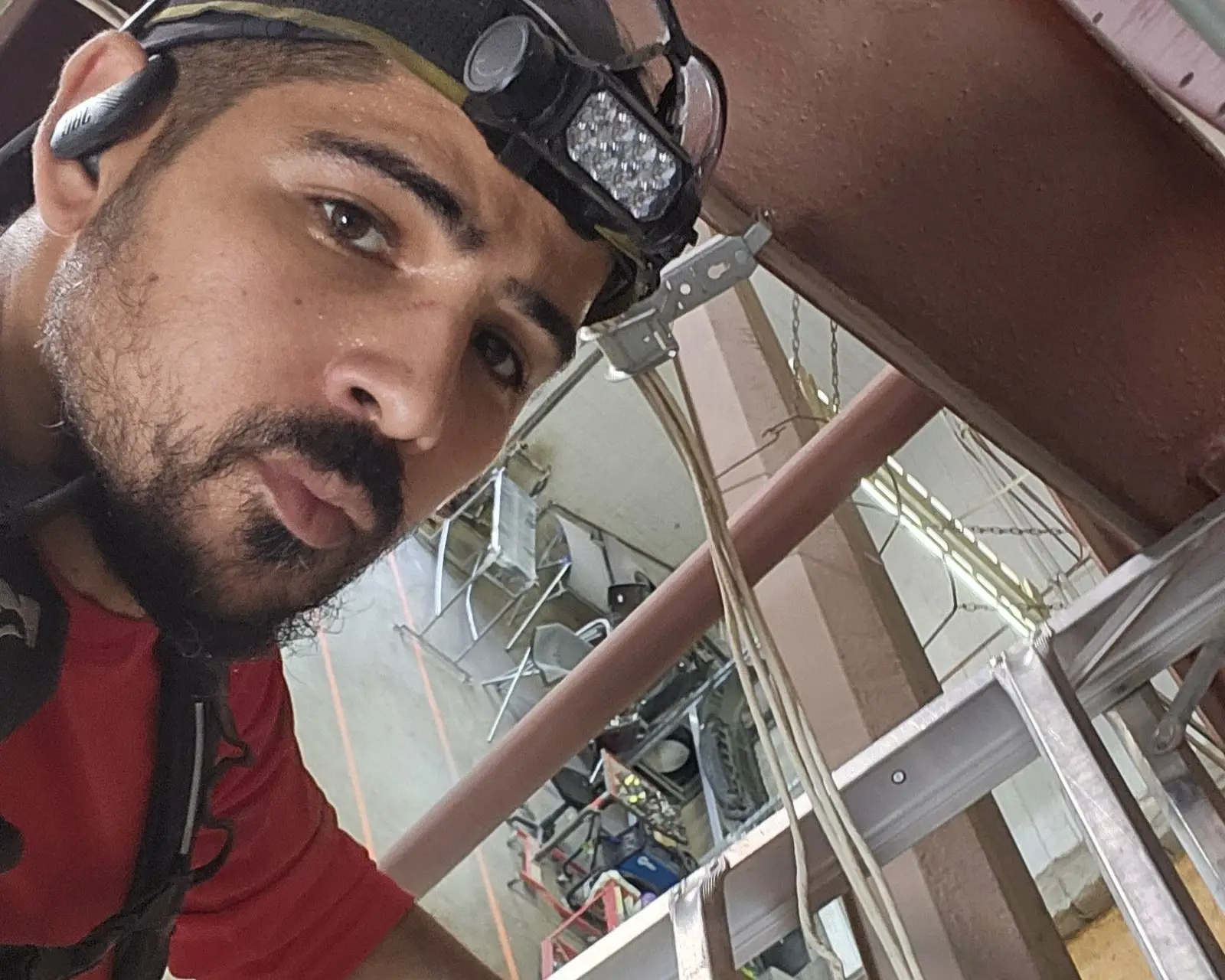 Joshua on a ladder working among steel framing with cables