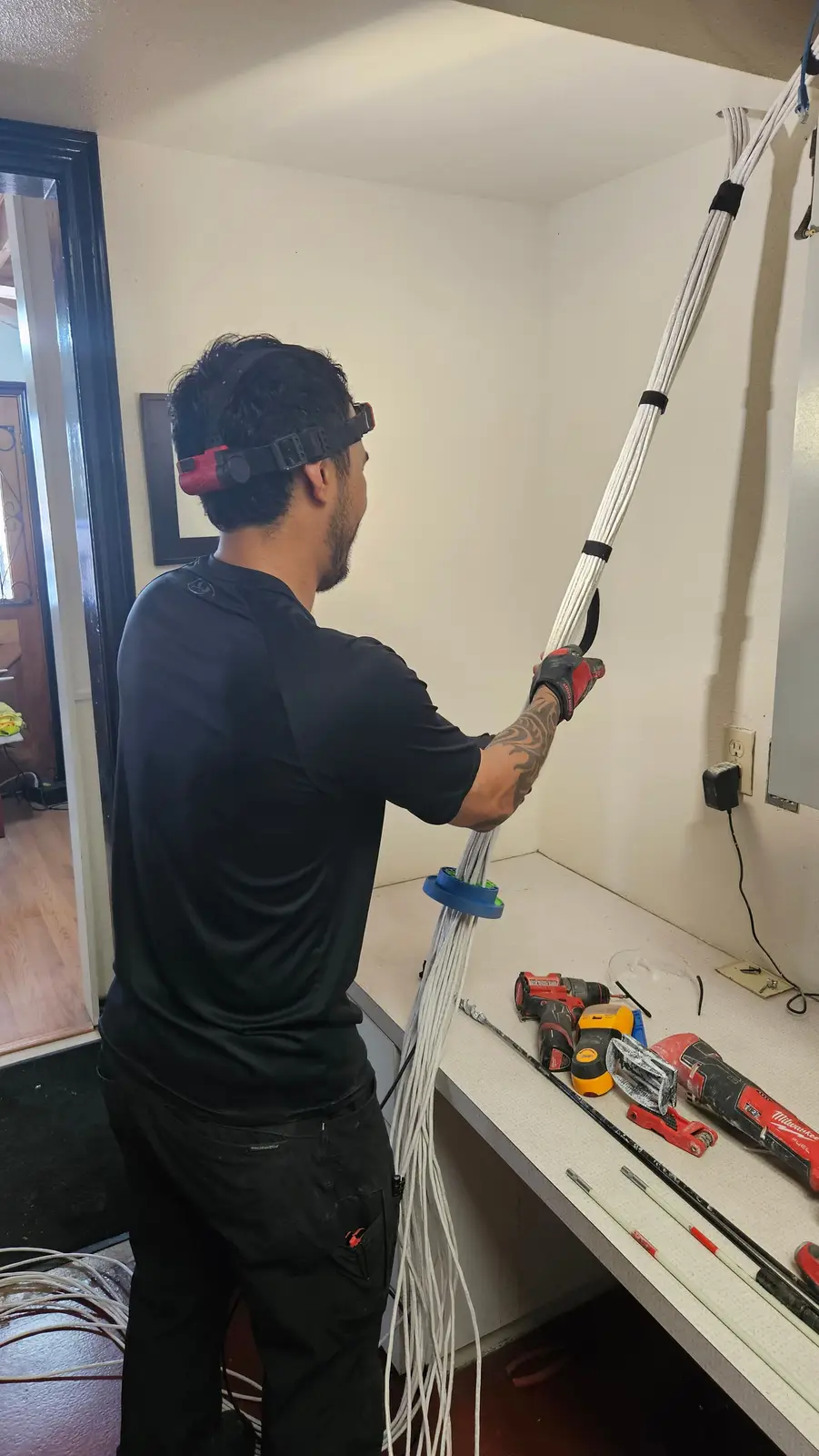 Technician pulling a bundle of cables up into the ceiling