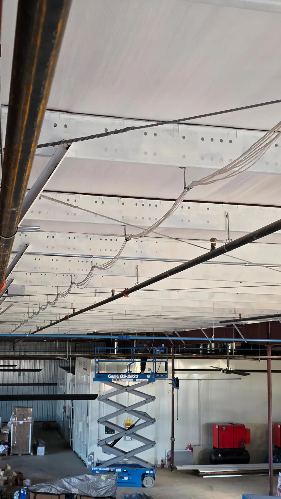 Cable bundles supported by J-hooks along a warehouse ceiling