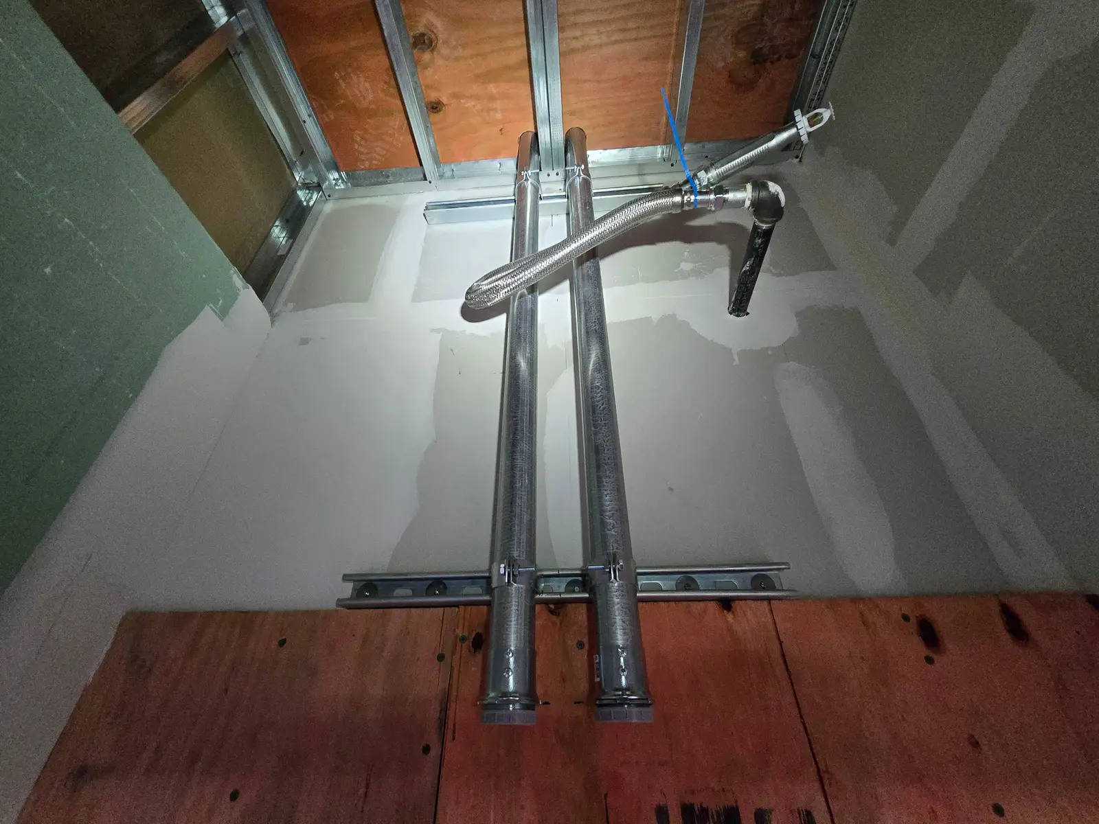 Two EMT conduits on strut running up an unfinished wall
