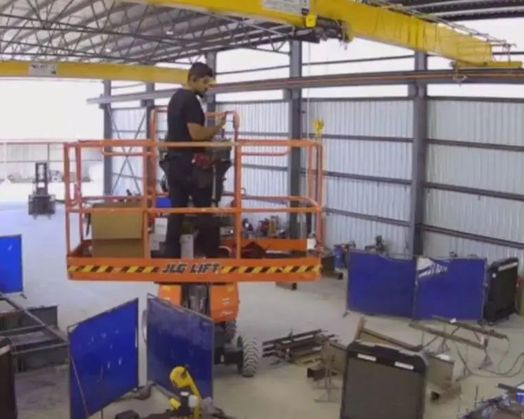 Joshua on a scissor lift inside a steel fabrication building