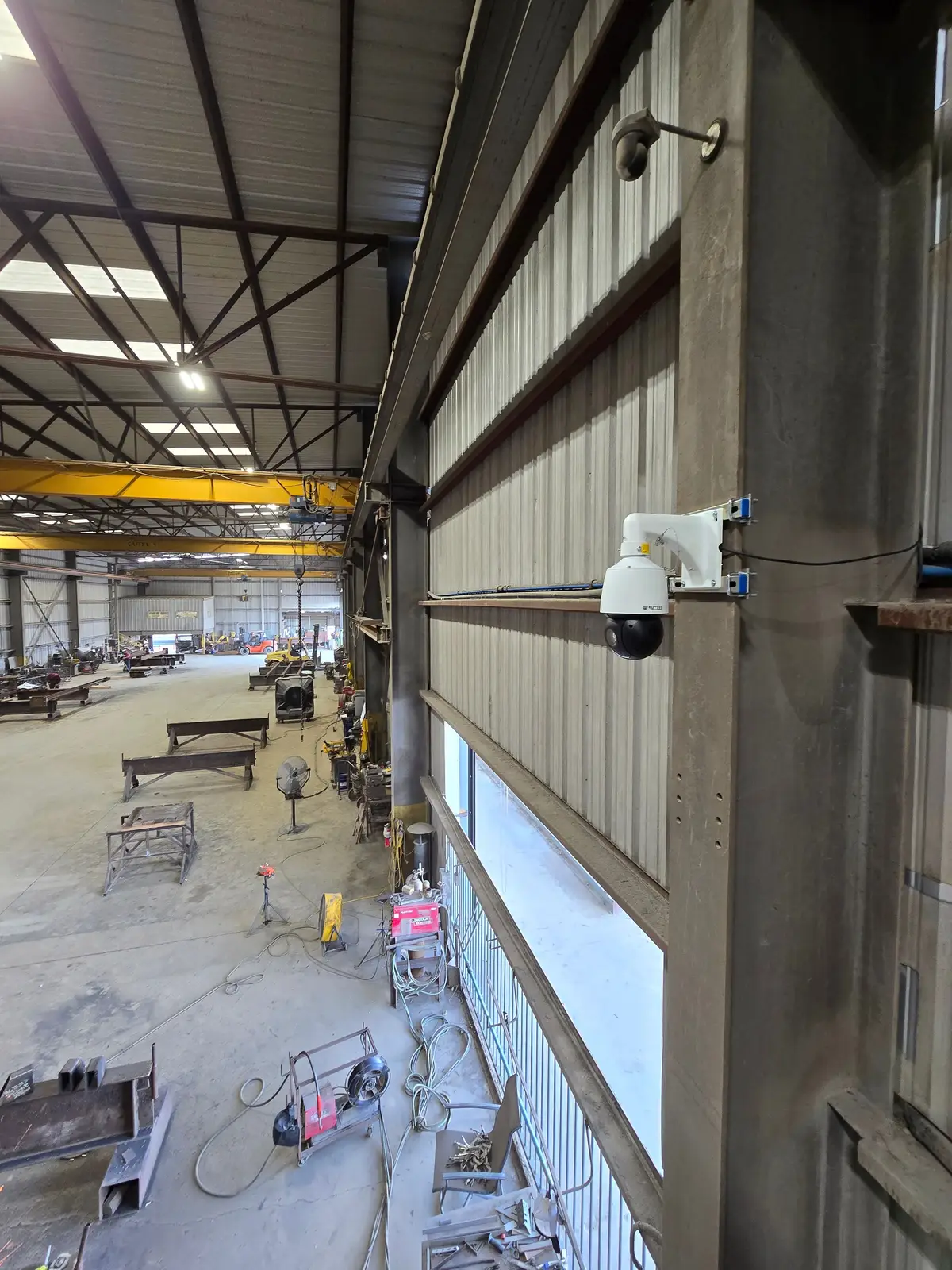 PTZ camera on a steel column overlooking a long fabrication floor