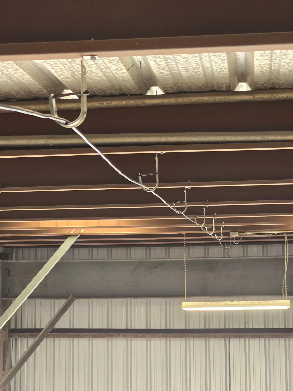 Cable supported by hangers along roof purlins