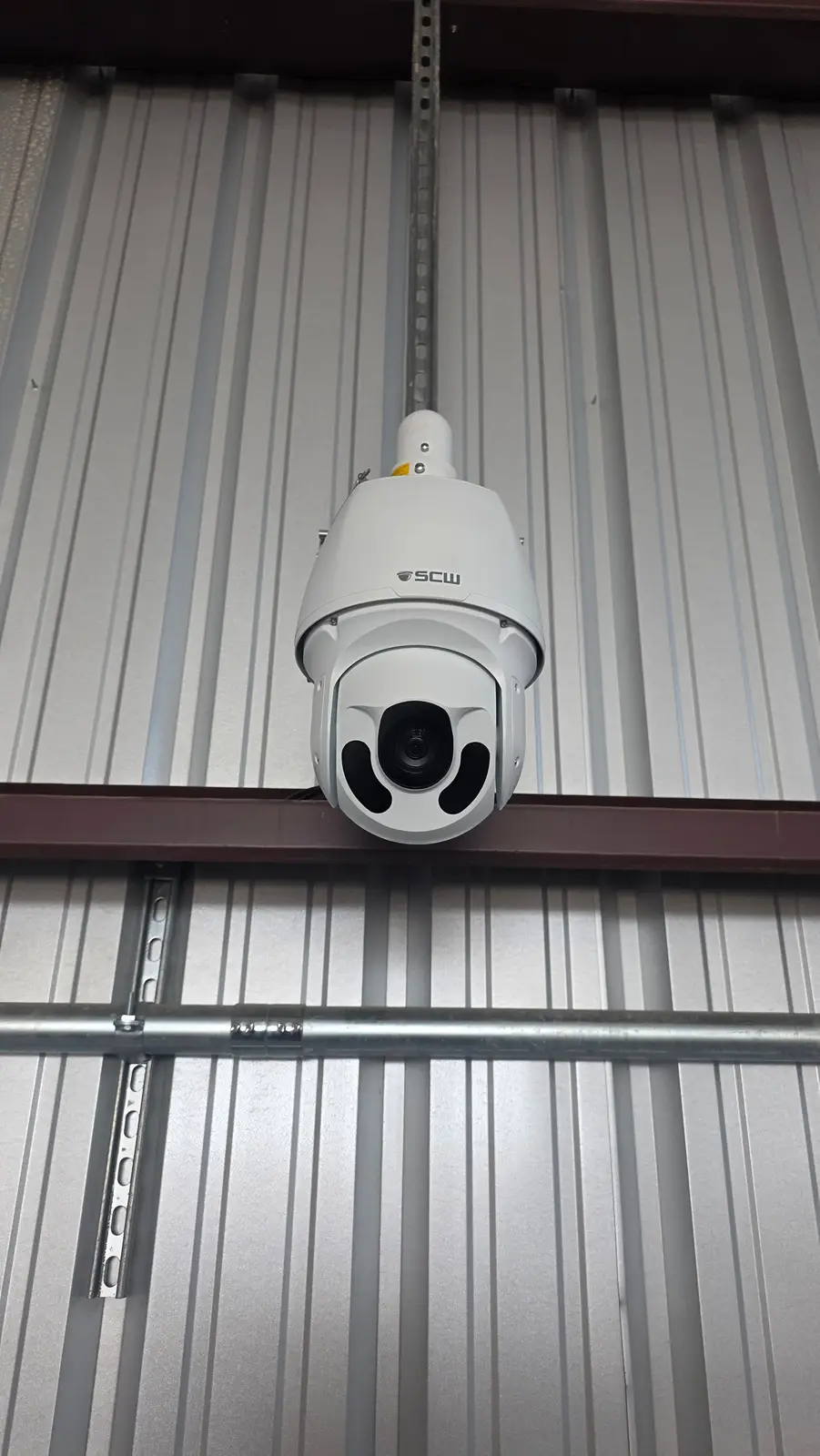 PTZ camera hanging from strut on a metal building wall