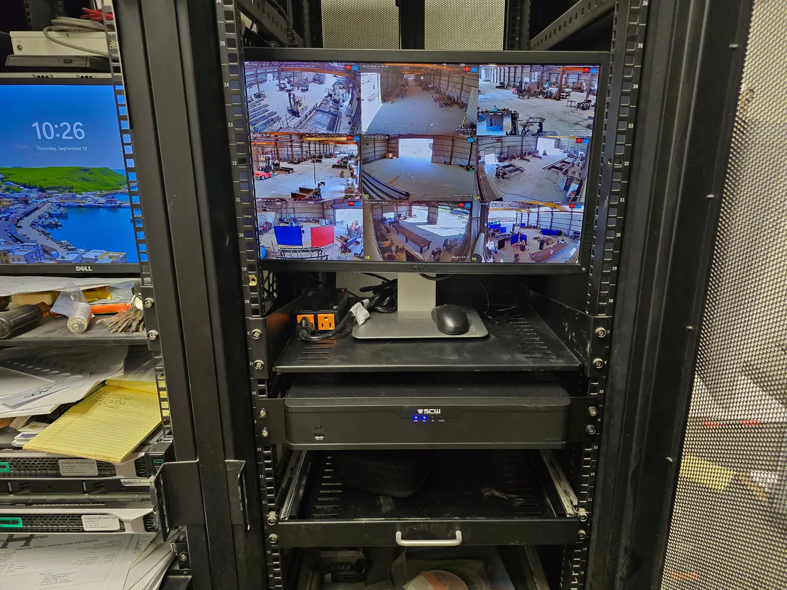 Rack-mounted recorder below a monitor showing a grid of camera views